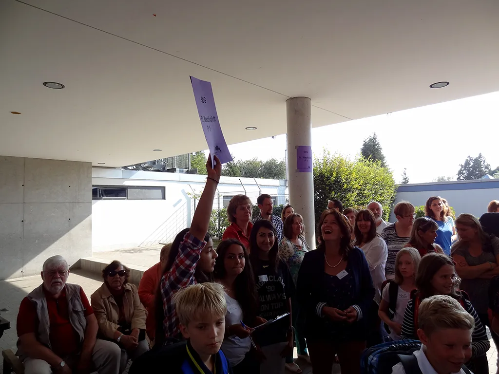 Personen halten ein lila Klassenschild in die Höhe.